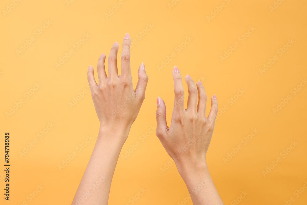 Woman hands in the air over yellow background Woman hands in the air over yellow background