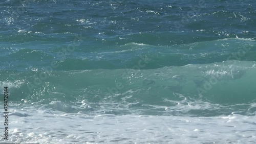 Slow motion waves forming and breaking on the shore of a beach in summer. Shallow depth of field.