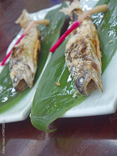 Japanese shioyaki aji salt-Grilled ayu sweetfish on bamboo leaves decorated with hajikami pickled ginger sprouts photo