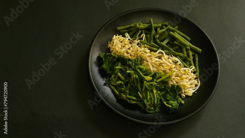 Urap, Indonesia traditional food served on plate. Salad dish consist of steamed vegetables such as sprouts, long beans, and mustard with seasoned and spiced grated coconut. photo