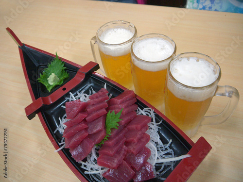 Tuna Sashimi or Funamori served in  gunkan boat shaped platter with three glass of beer photo