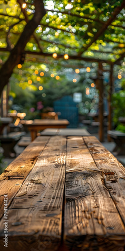 A wooden table sits under a garden canopy, surrounded by plants and sunlight © Nadtochiy