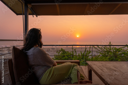 Mature young Indian enjoying sunset at Goa sea beach while sitting in a comfortable couch