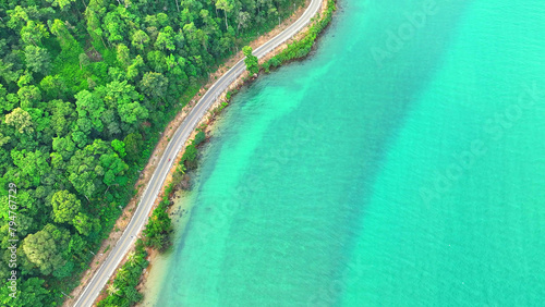 A mesmerizing tropical coastal road  weaving through vibrant greenery  kissed by crystal-clear sea waters. Travel and nature concept. Ko Chang  Trat Province  Thailand.  