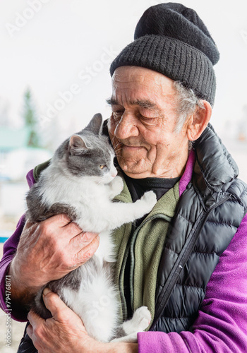 Old Russian man holding his cat and smiling