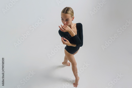 portrait of a young ballerina in a black bodysuit shows ballet steps top view