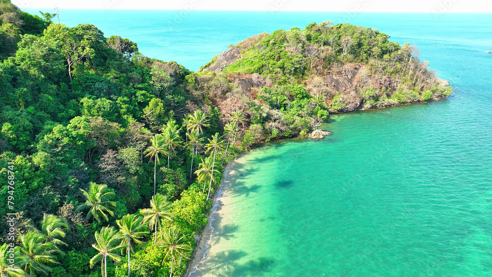 Emerald coastline, sandy shores, and coconut trees dancing under the sun on a tropical island. Nature's beauty captured from above. Wildlife conservation concept. Ko Chang, Thailand. 
