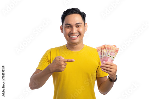 Happy young Asian man pointing finger at money in his hand isolated on white background. Profit and wealth concept