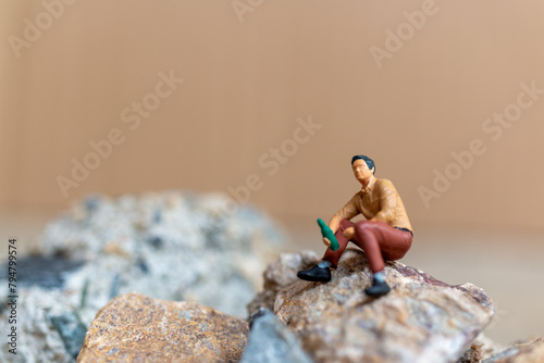 Miniature people , A young man sipping beer while sitting on the rock