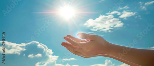 opened both hands fingers of a woman applying reiki healing against the background of a bright sun blue sky and clouds
