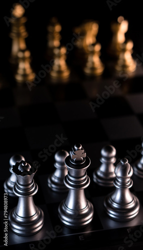 Silver chess pieces against blurred golden backdrop.