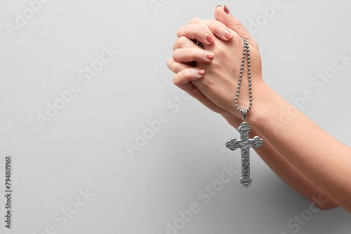 Female hands praying holding a silver vintage rosary on white background. Easter festival. Faith. Christian. Jesus