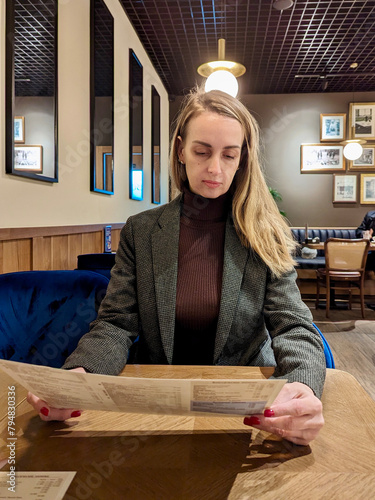 Portrait of a business woman looking at a menu in a cafe indoors.