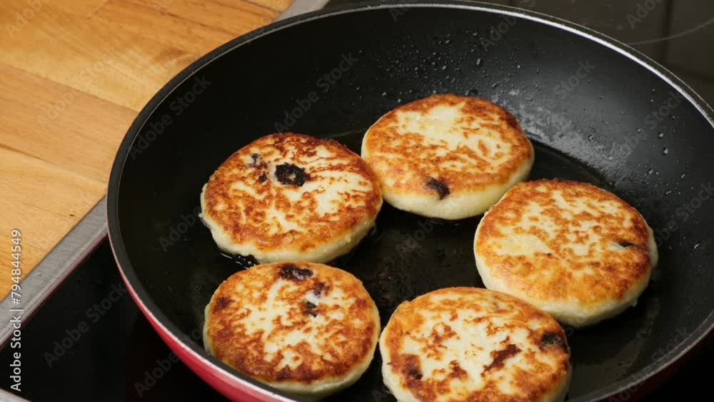 Woman opens the glass lid of a frying pan and you can see the fried cottage cheese fritters. Process of cooking homemade food. Preparing healthy tasty breakfast cheese cakes. Woman opens the glass lid of a frying pan and you can see the fried cottage cheese fritters. Process of cooking homemade food. Preparing healthy tasty breakfast cheese cakes.