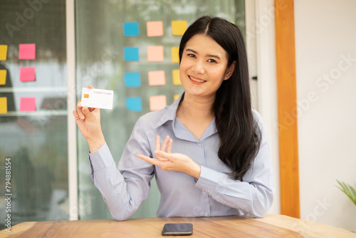 Asian girl shopping online holding credit and using smartphone enter their card number in the mobile phone app to purchase and payment in internet store