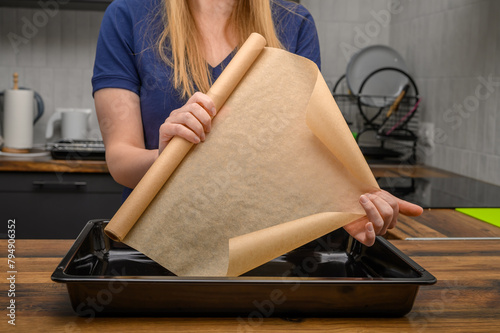 Kobieta trzyma w dłoniach rolkę brązowego papieru do pieczenia