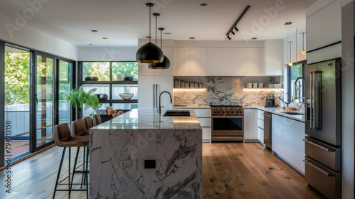 A modern kitchen with white cabinets and marble countertops. The kitchen is well-lit and has a clean, minimalist design. The stainless steel appliances, including the refrigerator and oven