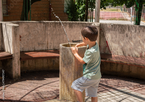 Child playing at fountain in a public park at city. © cunaplus