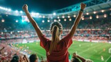 back view of female fan celebrating goal in football stadium.