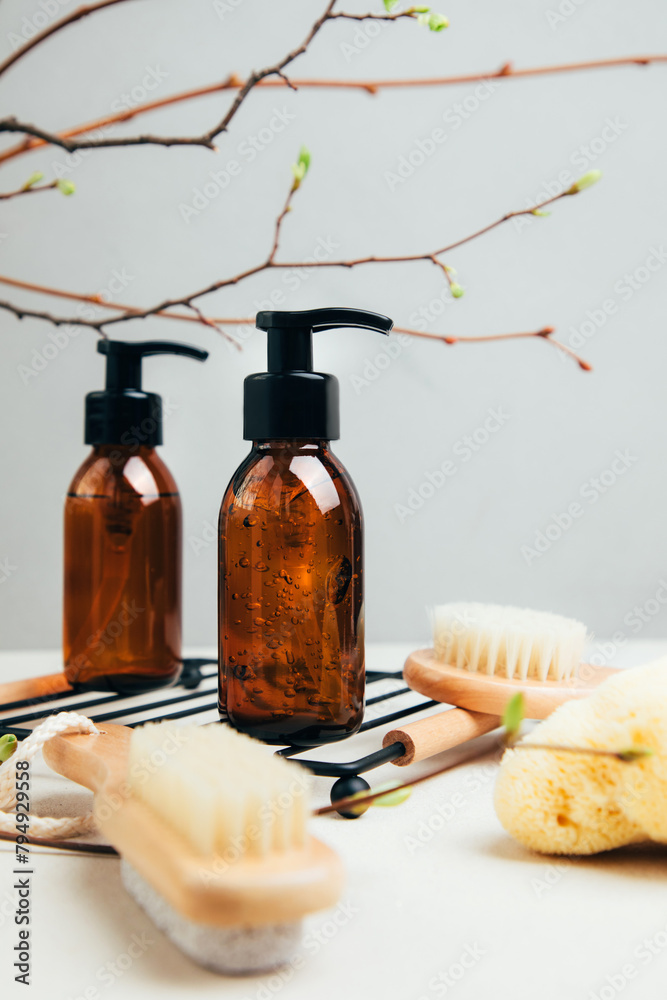 Set of natural cosmetics. Amber bottles with facial, bath liquid on a concrete background with young twigs of a tree. Front view - obrazy, fototapety, plakaty 