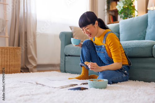 Woman reading newspapers, eating cookies and drinking coffee at home