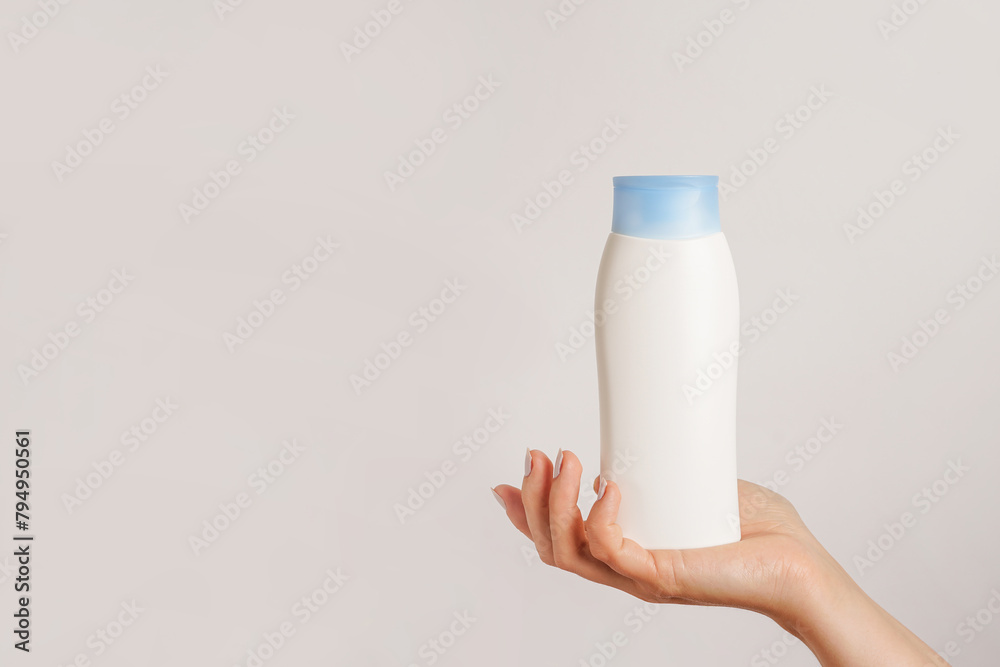 Woman hand holding white bottle of shampoo or hair conditioner on white background, copy space - obrazy, fototapety, plakaty 