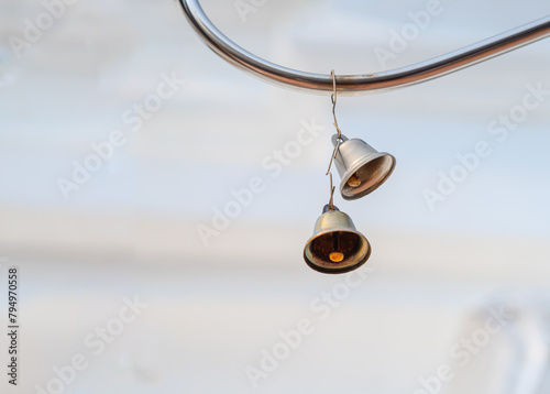Foto A small, cute, rusted silver bell rests against an iron railing next to a white concrete wall