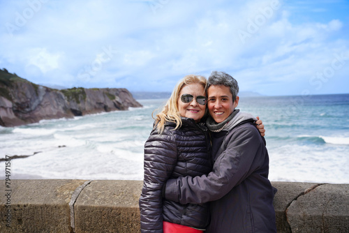 mother and daughter smiling looking at camera on a Spanish beach. Two women of the family