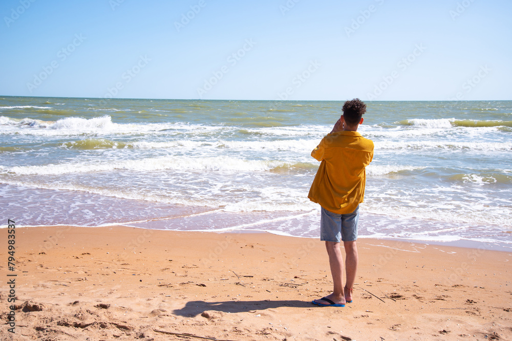 A young attractive man is photographed by the sea.