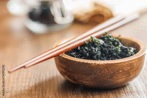 Dried wakame seaweed in bowl on wooden table. © Jiri Hera