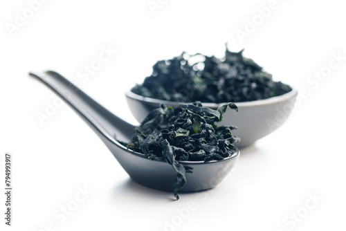 Dried wakame seaweed in spoon isolated on white background.