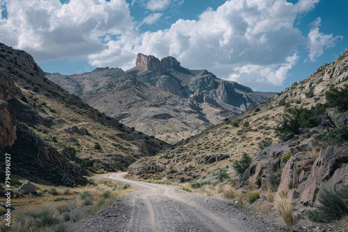 Desert mountain landscape with a dirt road curving between rocky cliffs