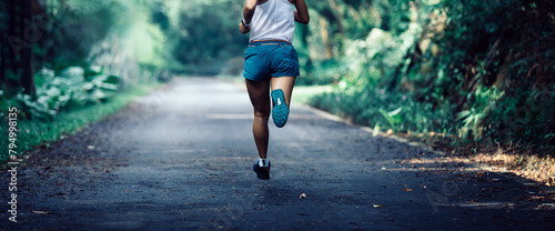 Fitness sportswoman runner running on tropical forest trail