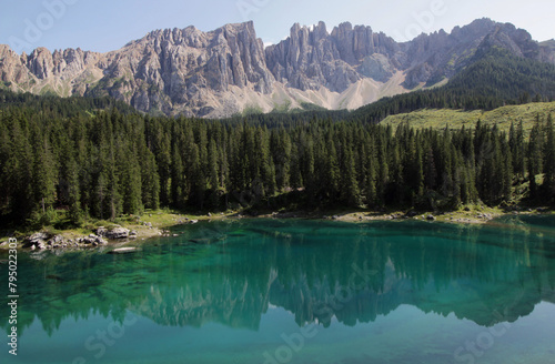 Panoramic photo of the landscape with Lago di Carezza lake and the Latemar mountain massif reflected in the lake and forest in the foreground in the Dolomites, South Tyrol region, Italy