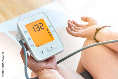 Close-up of young woman checking his blood pressure at home.