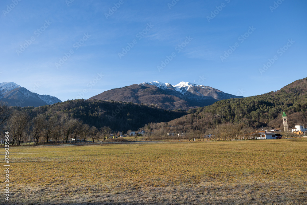ampia visuale panoramica che mostra un ambiente naturale di montagna nell'Italia a nord est, visto dal basso, in un'area di pianura, guardando verso una catena montuosa, in una mattina invernale