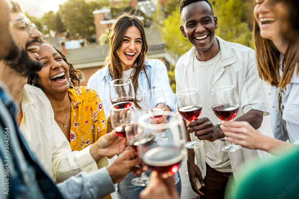 Obraz premium Happy friends toasting red wine glasses outside - Group of young people having bbq dinner party in backyard house