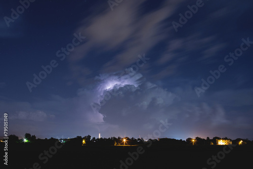 ampia visuale panoramica che mostra da lontano un temporale notturno, con fulmini, mentre si sposta sopra il territorio nel nord est Italia