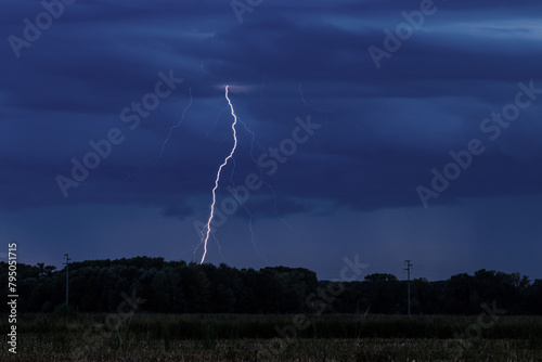 vista in primo piano di un fulmine che colpisce la terra durante un temporale estivo serale sopra un'area naturale nel nord-est Italia photo