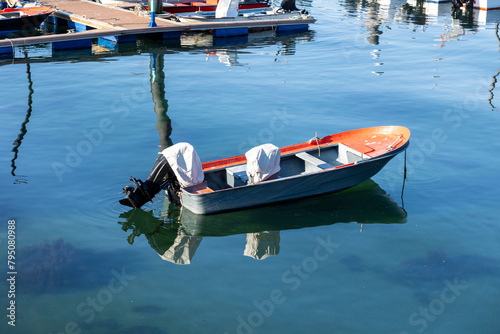 A serene view of a busy harbor in Fisterra Spain filled with various boats, flanked by a town, under the vast expanse of a clear blue sky, depicting tranquility and daily life photo