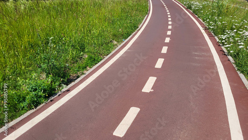 A red synthetic treadmill or bicycle path with white markings, with a turn