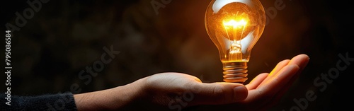 A person holding an incandescent light bulb in their hand against a plain background photo