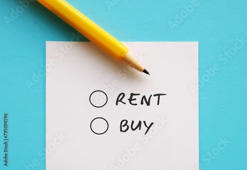 Note on blue background with pen writing RENT OR BUY, concept of financial management on major life decision, buying a home or vehicle, compare pros and cons of owning vs renting