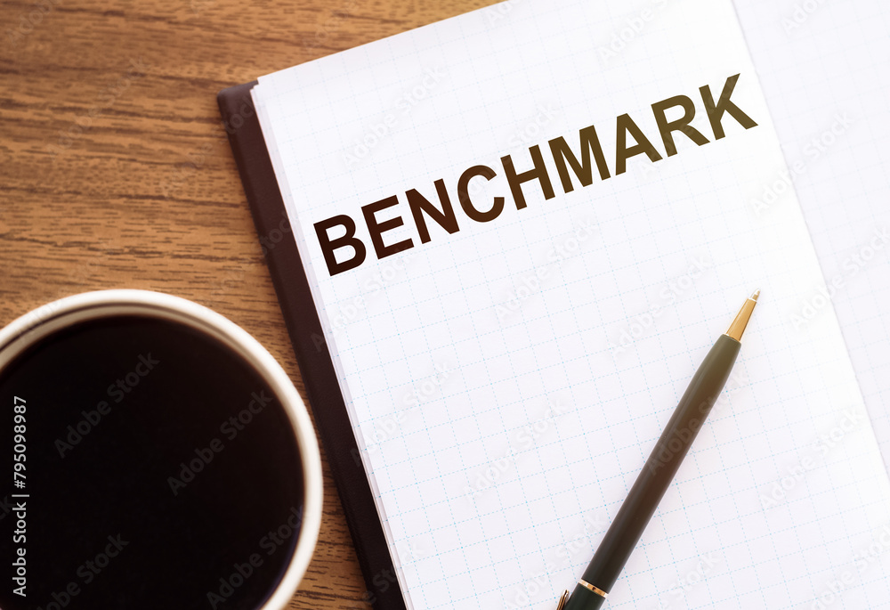 Notebook With BENCHMARK Text Beside a Coffee Cup on a Wooden Table Notebook With BENCHMARK Text Beside a Coffee Cup on a Wooden Table