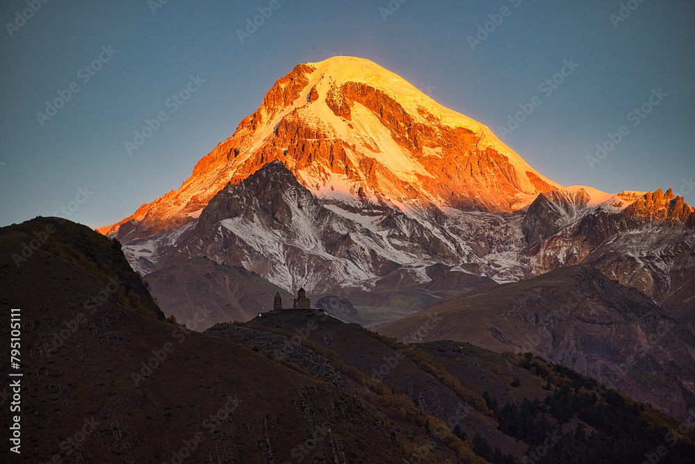 Glowing Mount Kazbek in Georgia with church in foreground 