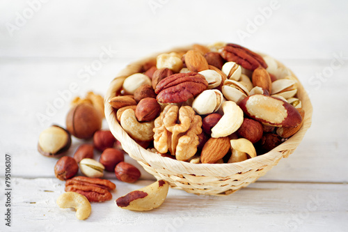 Nuts Mix in a Wooden Plate on a White Background. Wicker Basket full of Cashew, Walnuts, Hazeltuts, Peanuts, Brazilian Nuts, Pistachios