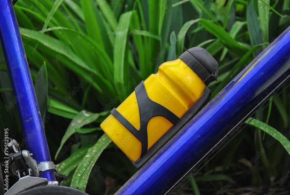 yellow bicycle water bottle on a bicycle close-up. green grass in the background. water bottle - obrazy, fototapety, plakaty 