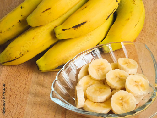 Banana slices cut in a bowl. A ripe of natural organic bananas over a wooden table