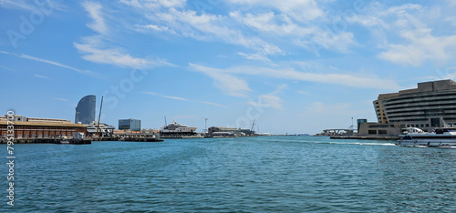 Wide angle view of a Mediterranean harbour in Spain  Europe  with docks  dry docks and open water under a blue sky with light clouds on a hot summer day.