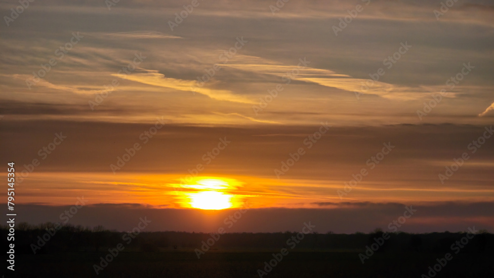 Clouds block the setting sun in the sky, creating a glowing amber afterglow Wunstorf Hanover Germany